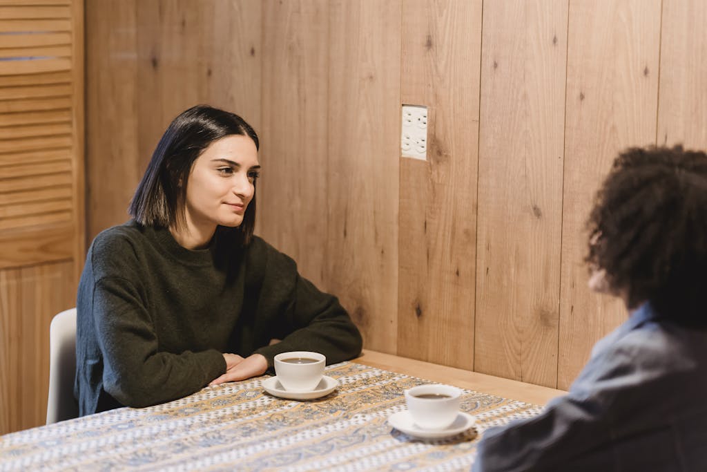 Best friends speaking at table with cups of coffee